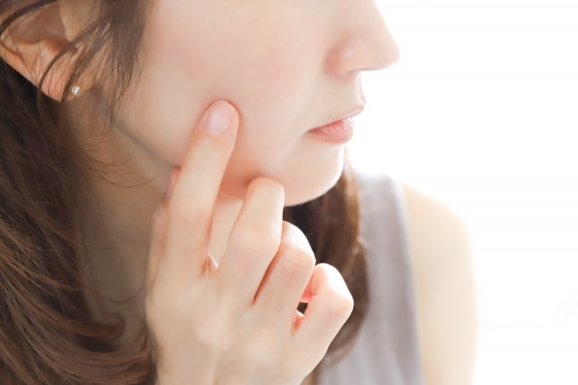 頬を指で触れている女性