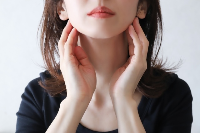 頬に触れてフェイスラインを気にしている女性