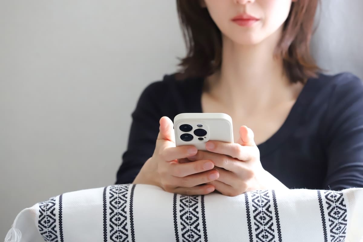 パートナーの行動を気にしながらスマホを確認する女性