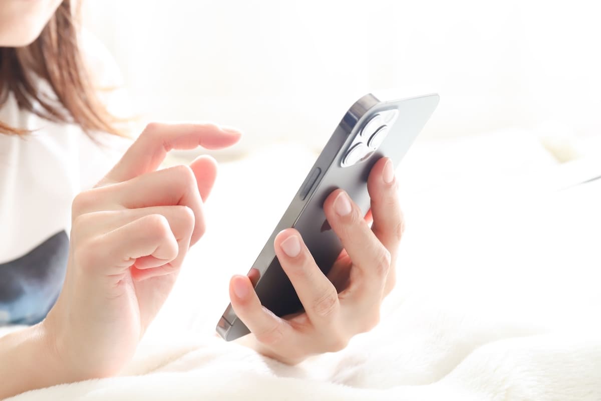 探偵事務所へ問い合わせるためスマートフォンを操作する女性の手元
