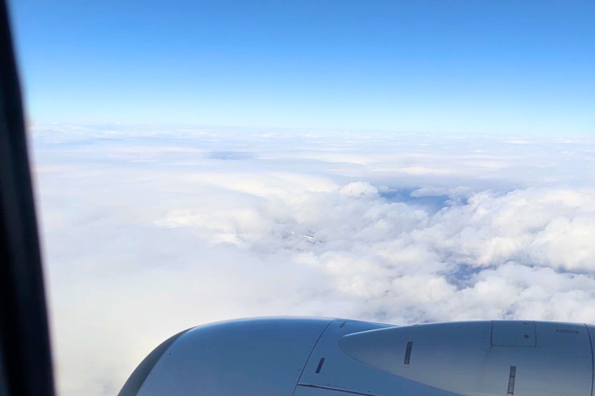 飛行機の窓から見える青空と雲、エンジン